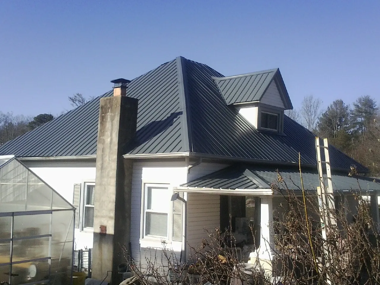 Dark blue standing seam metal roof on a white farmhouse with dormer — Slate & Tile Roof Repair by Roofing Brothers in Lindsay