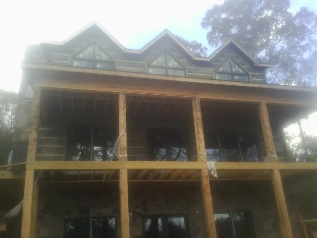 Dormers and porch framing on a large log home under construction — Roof Coating work by our crew in Lindsay