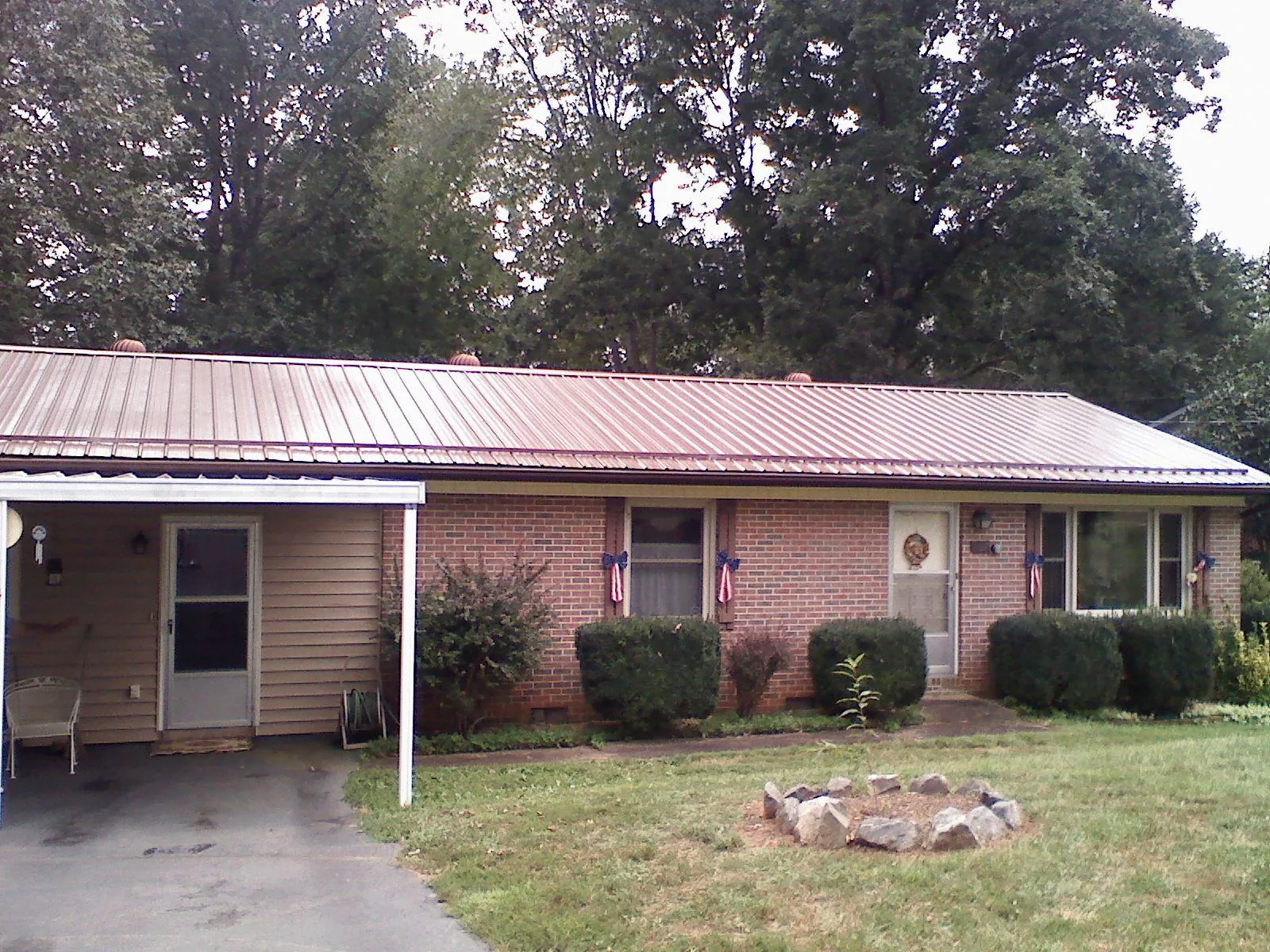 Bronze metal roof and carport on a brick ranch home — Roof Repair work by our crew in Lindsay