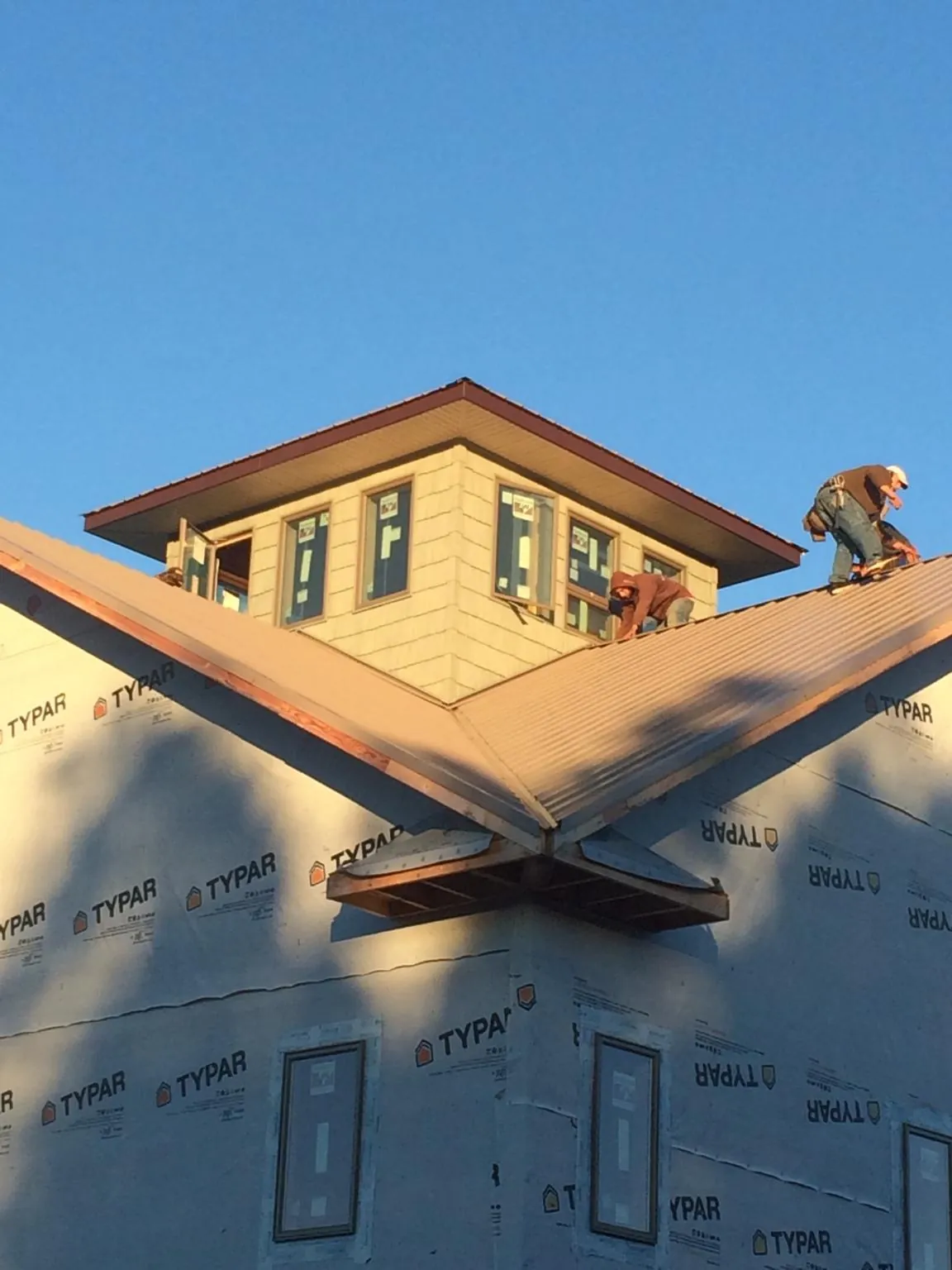 Roofers working around a rooftop cupola on a new metal roof at sunset — Roof Waterproofing in Lindsay by Roofing Brothers